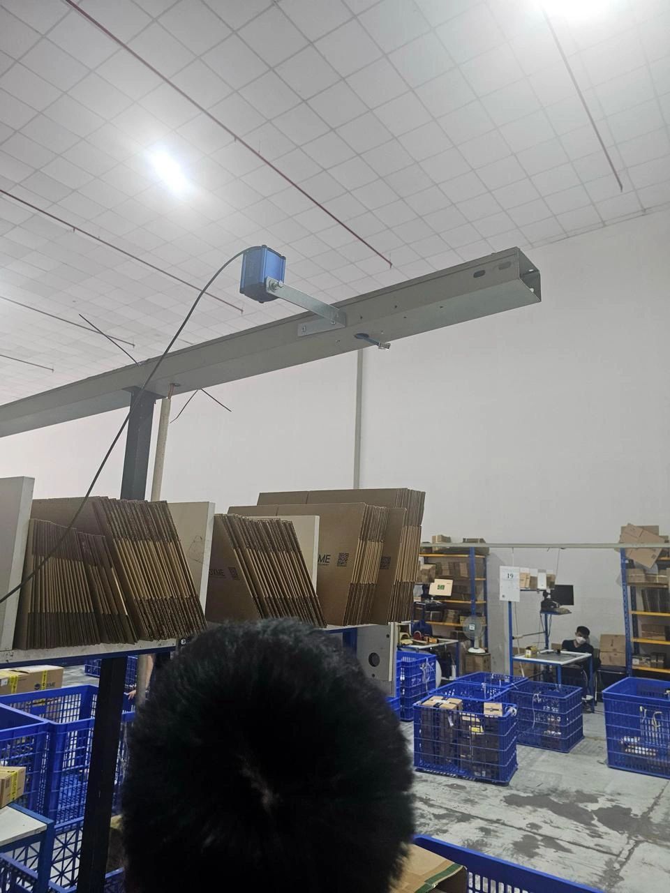 NetRay W8 packing camera mounted overhead above a packing bench in a fulfillment warehouse